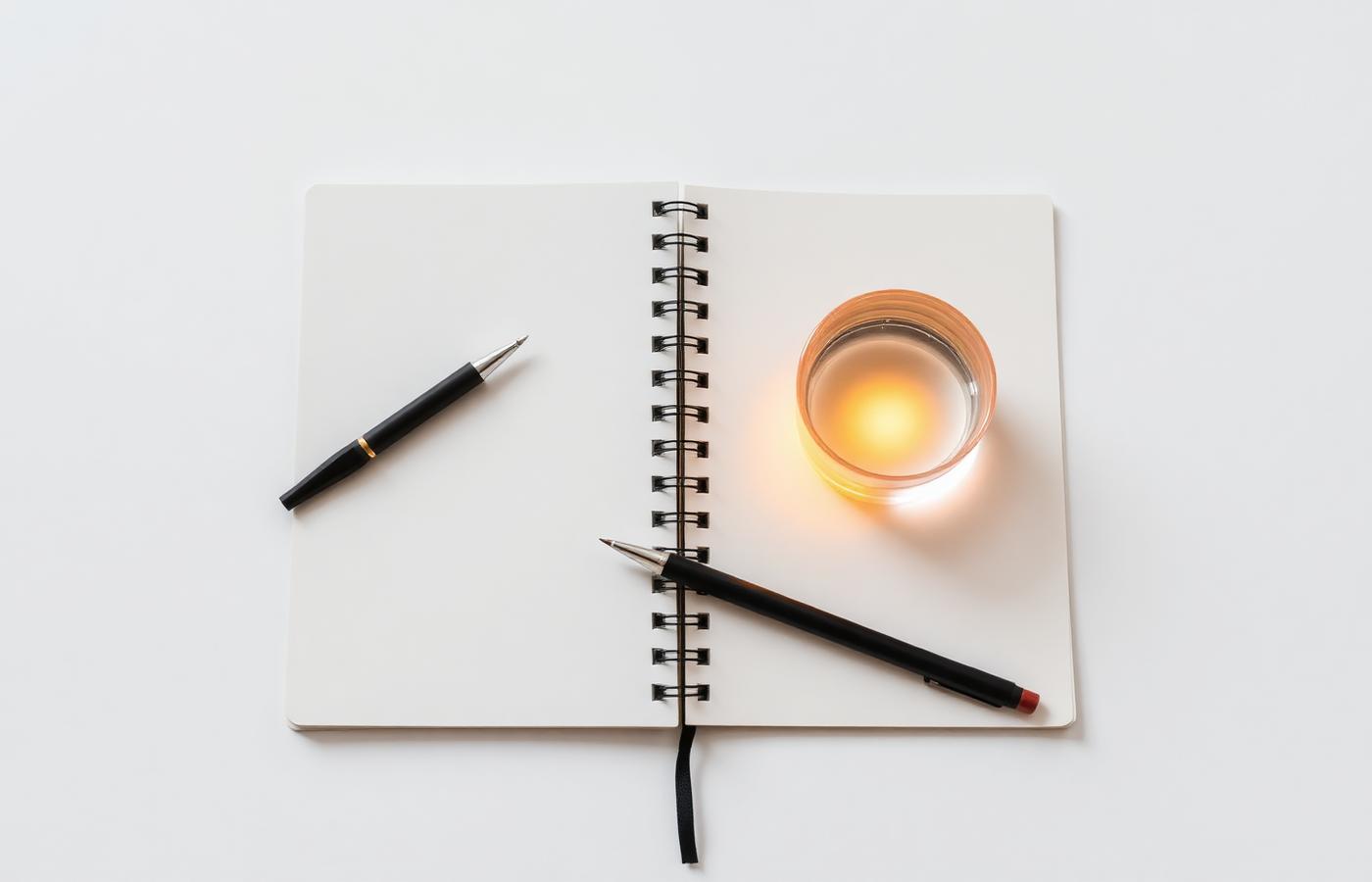 Open notebook and pen on a light desk illuminated by warm light